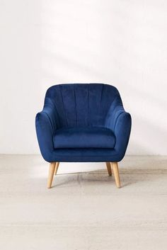 a blue chair sitting on top of a cement floor next to a white wall and wooden legs