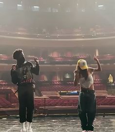 two people standing in front of an empty stage with one person holding a baseball bat