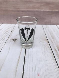 a shot glass with a tuxedo design on the side sitting on a wooden table