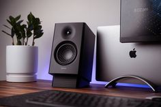 there is a computer on the desk with speakers next to it and a plant in front