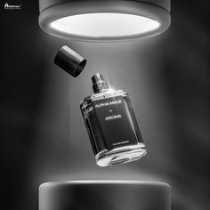 a black and white photo of a perfume bottle being suspended from a ceiling light fixture