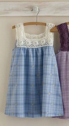 two dresses hanging on a clothesline with white and purple laces, one in blue and the other in pink