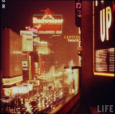 a city street filled with lots of traffic and tall buildings covered in neon signs at night