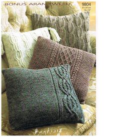 three knitted pillows sitting on top of a couch in front of a phone screen