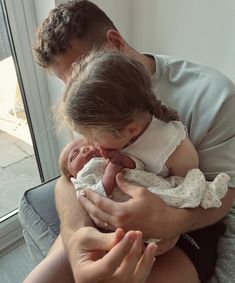 a man holding a baby in his arms while sitting next to a woman on a couch