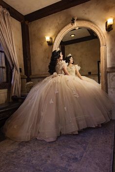 two women dressed in gowns sitting on a bed with their backs to each other