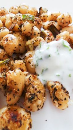 a white plate topped with potatoes covered in ranch dressing