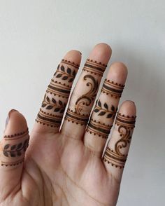 a woman's hand with hennap tattoos on it and two rings in the middle