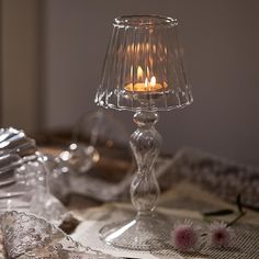 a candle is lit in a glass vase on a table with silverware and napkins