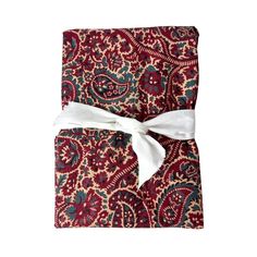 a red and blue paisley print napkin with a white bow on it's end