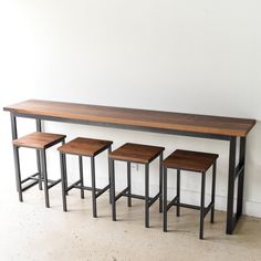 three stools and a table in front of a white wall