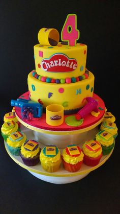 a birthday cake with cupcakes and toys on the bottom tier is decorated in bright colors