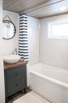 a bathroom with a sink, mirror and bathtub in it's center area