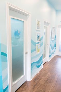 an empty room with blue and white wallpaper, wood flooring and two doors