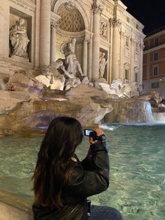 a woman is taking a photo of the water fountain