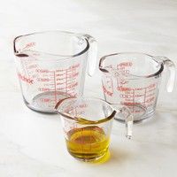 three measuring cups filled with liquid on top of a white counter next to an orange measuring cup