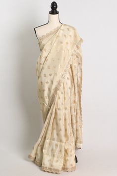 Elegant and luxurious, this Tissue Crepe Designer Saree in Cream and Gold is a stunning addition to any wardrobe. The delicate cream color is enhanced by intricate gold detailing, creating a truly regal look. The designer touch is evident in the exquisite motifs and embellishments, making this saree perfect for special occasions and formal events. Whether you're attending a wedding, festival, or simply want to make a statement, this saree is sure to turn heads and leave a lasting impression. Color : Cream and Gold.    Blouse Piece : Yes ( cut and separated from the saree ). Fall Pico : Yes.  Care: Dry-Clean Only. Festive Beige Pre-draped Saree, Cream Chanderi Bollywood Blouse Piece, Beige Pre-draped Saree With Zari Work, Fitted Cream Saree With Dupatta, Beige Pre-draped Saree For Festive Occasion, Cream Pre-draped Saree For Festive Occasions, Cream Saree With Resham Embroidery, Cream Pre-draped Saree With Zari Work, Festive Cream Saree Blouse Piece