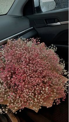 a bunch of pink flowers sitting on the dashboard of a car