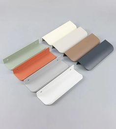 four different colors of paper on a gray surface with one folded up and the other closed