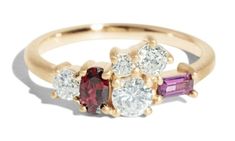 three stone ring with two different colored stones on the side and one white diamond in the middle