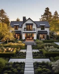 a large white house surrounded by trees and bushes with lots of greenery on each side