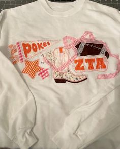 a white shirt with patches on the front and bottom that says pokes zita