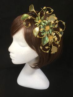 Green floral fascinator vine perfect for the guest or bride who is looking for a beautiful bespoke design. This design is a beautiful selection of glass effect leaves and flowers teamed with crystal swirls and set onto a gold ribbon base tiara band. As with all our designs, this piece can be made exact to the image or in any colour combination to match in with your outfit. If a specific colour is required customers can message over an image of their outfit and accessories, or if time allows cust Green Wedding Headband Hair Accessory, Green Headband For Wedding, Green Wedding Headband, Green Fascinator With Handmade Flowers For Party, Whimsical Crown Headpiece For Wedding, Whimsical Wedding Crown Headpiece, Green Headband Mini Hat For Wedding, Elegant Green Hair Accessories For Wedding, Green Headband Fascinator For Wedding