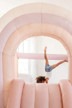 a woman is doing tricks on an inflatable obstacle while standing on one leg