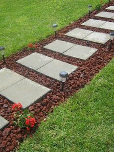 a garden path made out of stones with flowers in the center and two lights on each side