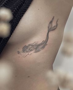 a woman's stomach with a tattoo design on the side of her body, which has a fish swimming in it