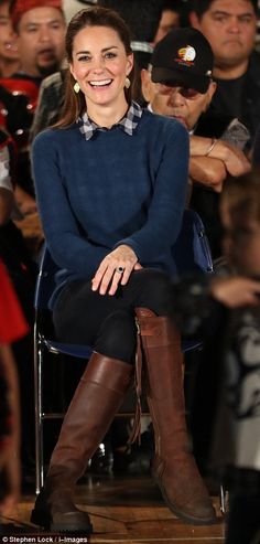 a woman sitting on top of a chair in front of a crowd