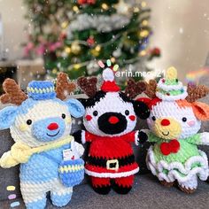 three knitted stuffed animals sitting next to each other in front of a christmas tree