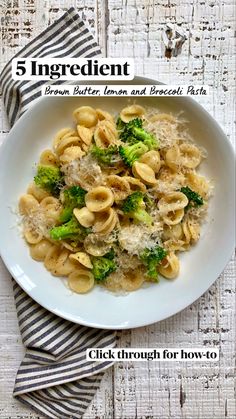 a white bowl filled with pasta and broccoli on top of a wooden table