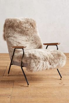 a chair with a sheepskin seat and back rest on a wooden floor in front of a white wall