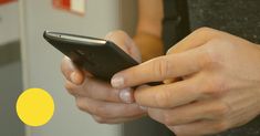 a close up of a person holding a cell phone with yellow circles in the background