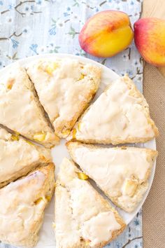 a white plate topped with scones covered in frosting next to two peaches