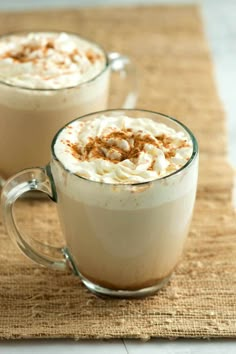 two mugs filled with whipped cream on top of a burlly place mat