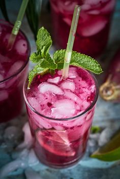 two glasses filled with ice and mint on top of a table