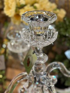 a clear glass candle holder sitting on top of a table next to some yellow flowers