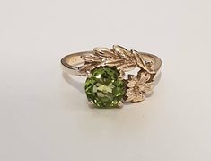 Peridot and gold ring- The genuine green Peridot is surrounded by a flower and leaves. The design is antique style that is further enhanced by the unique color of the Peridot. Ring is made in 10 carat yellow gold. The green Peridot is AAA quality measures 6.5x6.5mms and weighs 1.14 carats.   Ring size is K (Australian size) or 5 1/2 (US size). Ring is ready to ship in 1-2 working days.  We resize free of charge.  Please allow a couple of additional days for resizing. This ring can be custom made Antique Style Rings, Flower And Leaves, Leaves Design, Peridot Ring, Green Peridot, Precious Gems, Antique Style, Leaf Design, Unique Colors