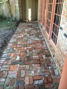 an old brick walkway is shown in front of a door and window with bars on it