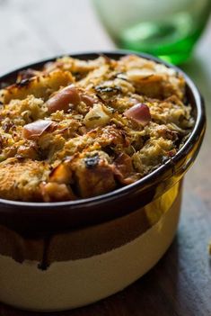 a casserole dish with meat and vegetables in it on a table next to some bread