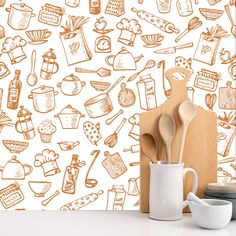 kitchen utensils and wooden spoons in front of a wallpapered background