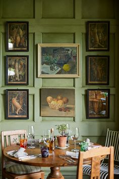 a dining room with green walls and pictures on the wall