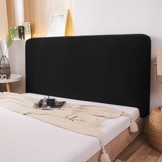 a bed with a black headboard and white sheets