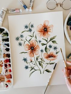 a person is painting flowers with watercolors