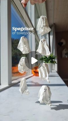 a person is holding up some white ghost decorations