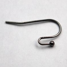 a metal hook on a white surface with a black ball hanging from it's end