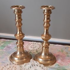 two brass candlesticks on a lace doily