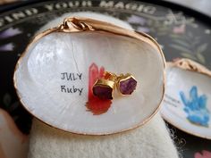 two small pieces of jewelry sitting on top of a white plate with writing on it